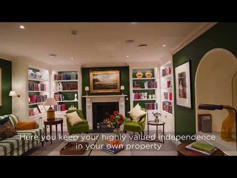Preview image for the video "Welcome to Audley Scarcroft Park" - A cozy living room with green walls, a fireplace, bookshelves, and comfortable seating. Text at the bottom reads, "Here you keep your highly valued independence in your own property..