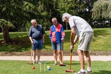 Seniors playing croquet on a sunny day