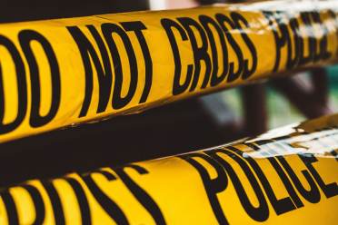 Close-up of yellow "Police Line Do Not Cross" tape stretched in multiple layers, blocking off an area.