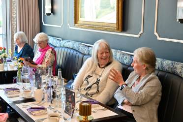 Four women seated at a table in a restaurant, conversing and laughing.