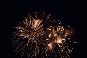 Golden fireworks exploding against a dark night sky.
