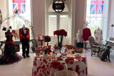 Room decorated with Union Jack flags, mannequins in formal wear, a table covered with poppy-themed items, and various baskets and accessories arranged around the display.