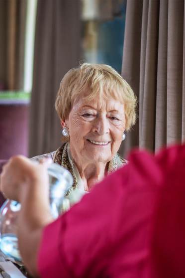 Woman smiles as carer pours water