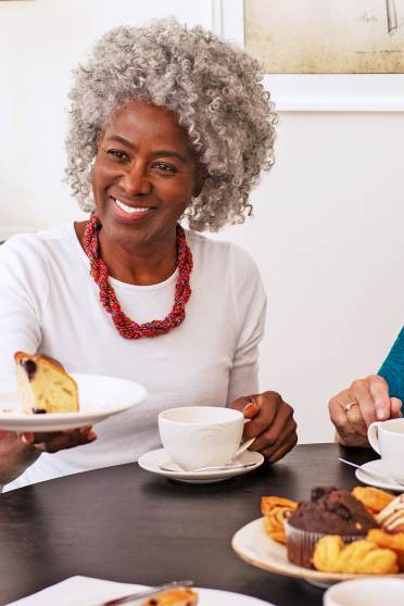 Two women enjoy tea and cake with a carer