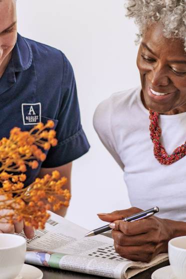 Woman solving crossword with carer