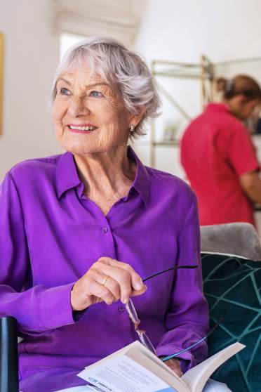 Woman reads while carer cleans room