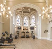 Gym equipment in high, bright room with stained glass windows