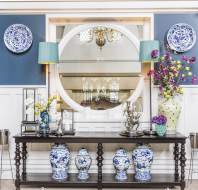 Blue-and-white porcelain, dark wood sidebard and large round mirror