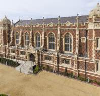 Red-brick mansion with arched windows and stone buttresses