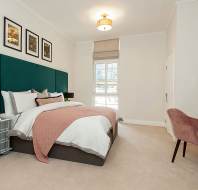 A bright bedroom with a blush pink blanket and a vanity table