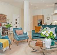 Living room with teal furniture and round glass coffee table