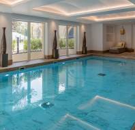 Indoor pool with loungers and large windows