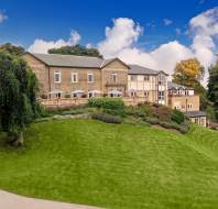 Stone manor house on hill with green lawn