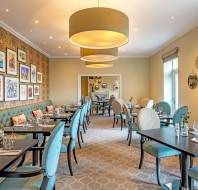 Long room with small tables and light blue chairs