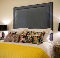 Bedside lamps with black shades. Bed with a mustard blanket.