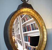 Bookshelves reflected in round wall mirror