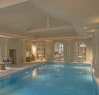 Softly lit blue pool with columns and arched windows