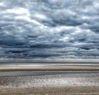Moody clouds over golden sands at low tide