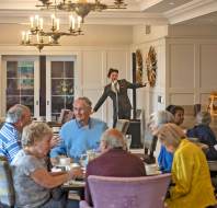 Guests around table are entertained by a crooner in 1950s clothes