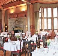 White tablecloths, stone fireplace and gothic bay window