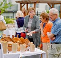 Customers inspect carved wooden items on stall