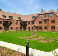 Red brick apartment block with lawn