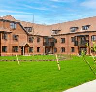 Red brick apartment block with lawn