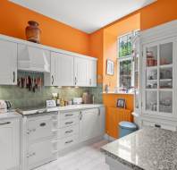 Kitchen with white cabinets and orange walls