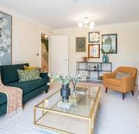 A bright room with mustard armchair and a bottle green sofa