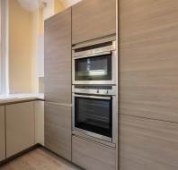 Modern kitchen with built-in double ovens, beige cabinets, a sink, and a window.
