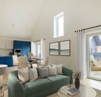 Modern living room with a green sofa, decorative pillows, and coffee table. Adjacent kitchen area with blue and white cabinetry. Large windows and a balcony door provide natural light.
