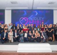 A large group of people posing on stage in formal attire at the Audley Spirit Awards event.
