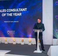 Person at a podium with "Sales Consultant of the Year" displayed on a screen in the background during the Audley Spirit Awards.