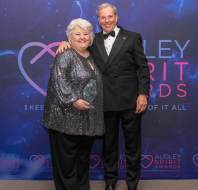 Two people in formal attire pose together at the Audley Spirit Awards. One holds an award.
