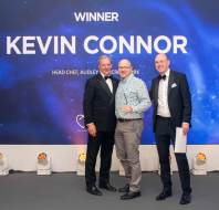 Three men in formal attire stand smiling in front of a backdrop with the text "Winner Kevin Connor, Head Chef, Audley Cooper's Hill York.