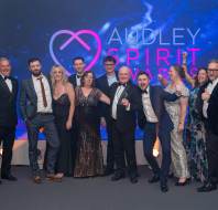 A group of people dressed in formal attire posing in front of a backdrop that reads "Audley Spirit Awards.