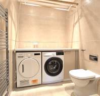Laundry room with a washer and dryer beneath a countertop, a toilet, a small sink, and a heated towel rail on beige tiled walls.