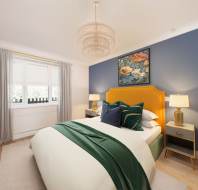 Bedroom with blue accent wall, bed with yellow headboard, green and white bedding, two bedside tables with lamps, and a window with gray curtains. A floral painting hangs above the bed.