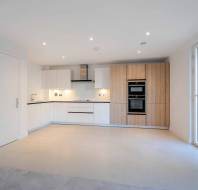 Modern kitchen with white and wood cabinetry, built-in appliances, recessed lighting, tiled flooring, and a large sliding glass door on the right.
