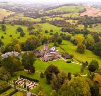 Aerial view of a large castle surrounded by extensive gardens and lush green countryside.