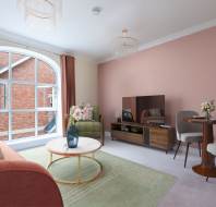 A modern living room with a pink accent wall, large arched window, red sofa, round coffee table, TV stand, and a small dining table with two chairs.