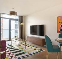 A modern living room with a sofa, TV, dining table with chairs, colorful rug, large window with curtains, and a bright painting on the wall.