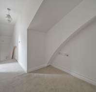 A white, carpeted landing with a sloped ceiling and a crystal pendant light.