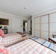 Two twin beds with plaid bedding in a bedroom with a sliding-door closet and a wooden chair.