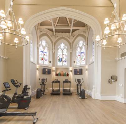Gym equipment in high, bright room with stained glass windows