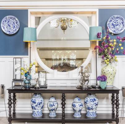 Blue-and-white porcelain, dark wood sidebard and large round mirror