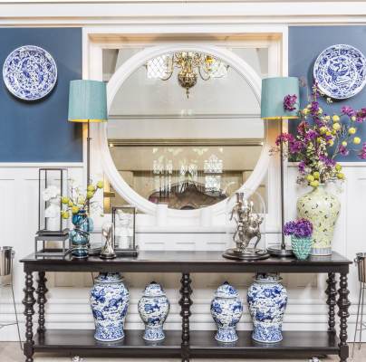 Blue-and-white porcelain, dark wood sidebard and large round mirror