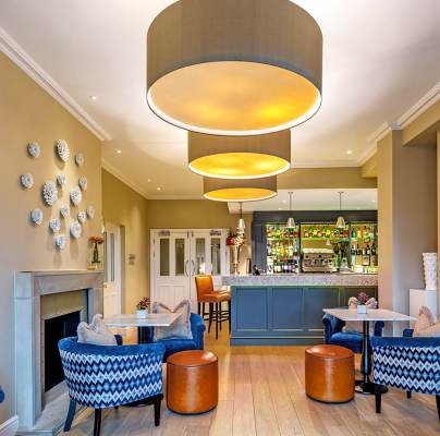 Bistro with blue armchairs, caramel leather stools and beige walls