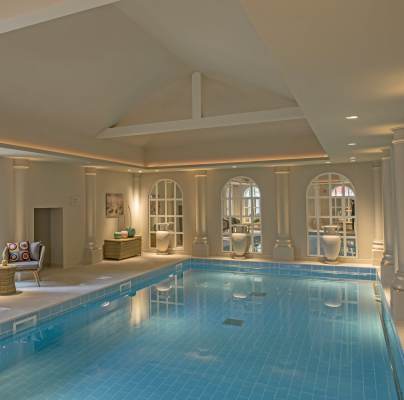 Softly lit blue pool with columns and arched windows