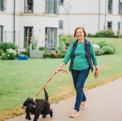 Woman walking a dog with a stick in its mouth
